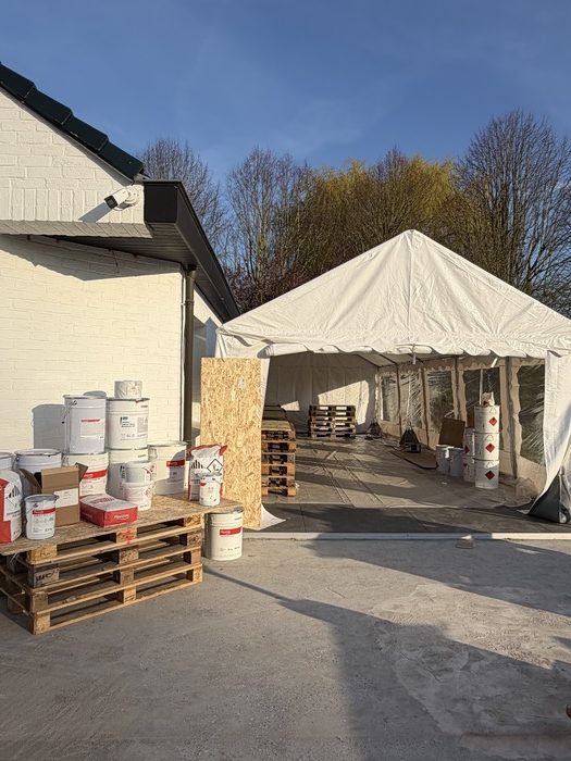 Le terrain d'application des démonstrations est dédié à la journée de formation métacrylate. Le terrain est prêt sous une tonnelle, et les produits Flowcrete sont sur la gauche, sur des palettes.